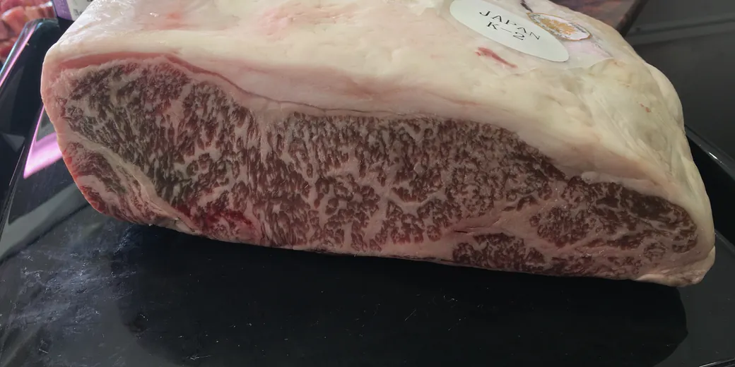 A piece of Japanese beef with dense marbling, its Japan origin seal visible, on a tray in the shop.