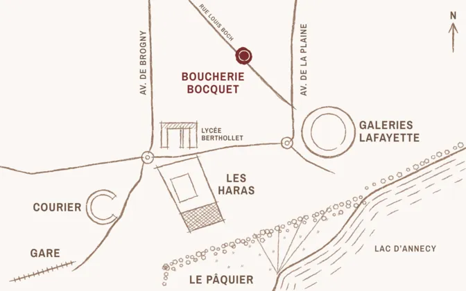 Pencil sketch map. Boucherie Bocquet, 16 rue Louis Boch, sits north of every landmark, between avenue de Brogny to the west and avenue de la Plaine to the east. Just south, the Lycée Berthollet. To the south-east, 250 m away, the round Galeries Lafayette building. To the south-south-west, 500 m away, Les Haras, with the Halle gourmande in its lower part. To the south-west, the Courier ring at 700 m, then the station at 950 m along avenue de Brogny. To the south-south-east, 800 m away, the Pâquier park on the shore of lake Annecy.