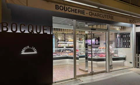The Boucherie Bocquet shopfront lit at dusk, Boucherie – Charcuterie sign and refrigerated windows, 16 rue Louis Boch in Annecy