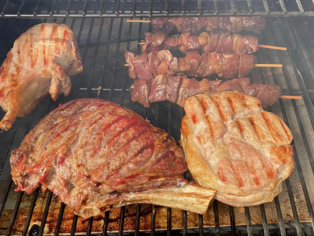 Au barbecue, une côte de bœuf, des côtes et des brochettes, marquées par la braise.