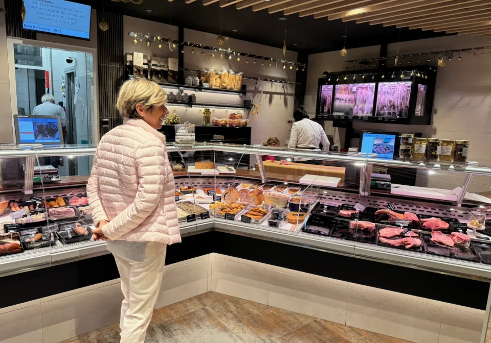 A customer at the refrigerated displays of Boucherie Bocquet, charcuterie and meat on display