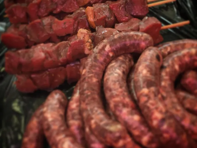 Coils of raw sausages and skewers, ready for the grill.